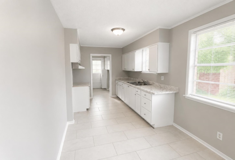 Kitchen featuring white cabinetry, stone-finish countertops, and a double-basin stainless steel sink