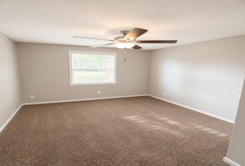 Room featuring neutral-toned walls, brown carpet flooring, and a ceiling fan with integrated lighting