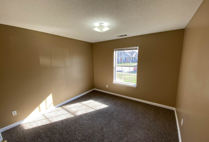 Room with neutral-toned walls, dark patterned carpet, and white baseboards