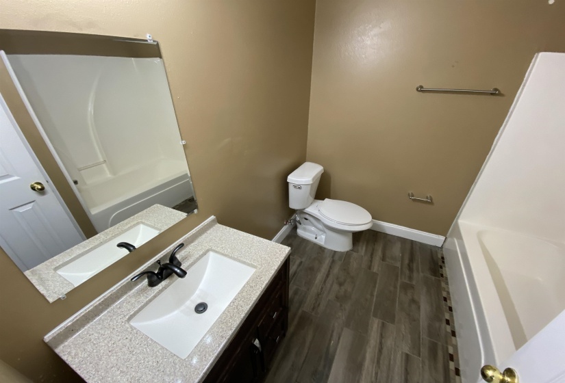 Bathroom featuring a dark wood-finish vanity with a speckled countertop, a rectangular undermount sink with a matte black faucet, and a large wall-mounted mirror