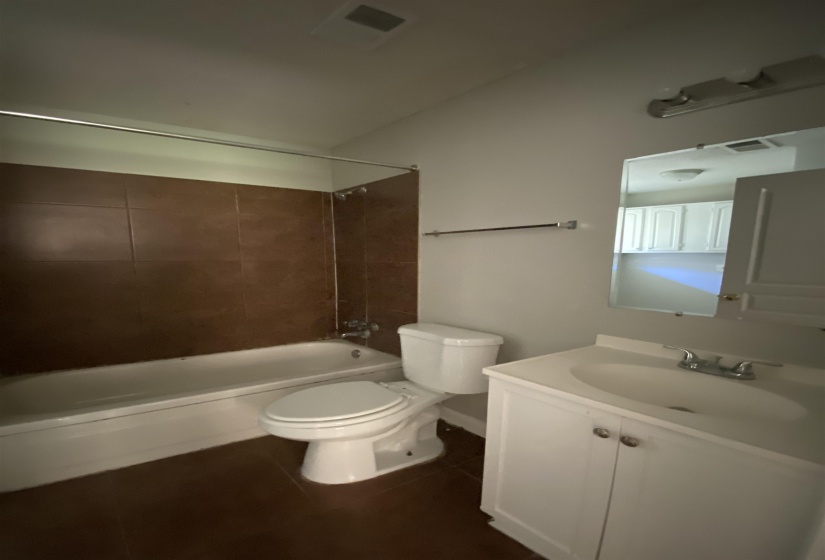 Bathroom featuring a white bathtub, brown tiled shower surround, and a white toilet