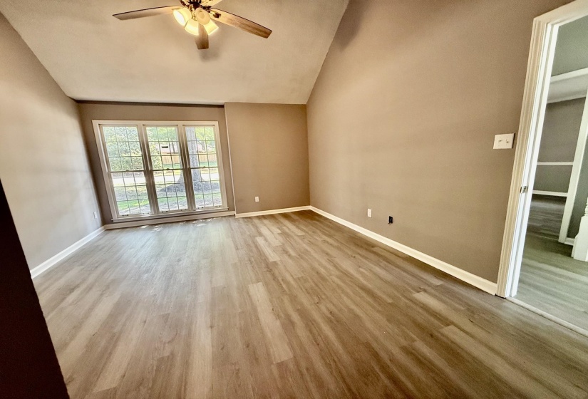 Room featuring wood-finish flooring, vaulted ceiling, and a ceiling fan with light fixture