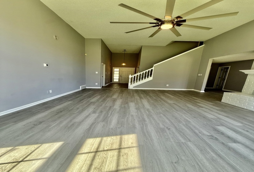 Spacious living area featuring wood-finish flooring, high ceilings, and a modern ceiling fan