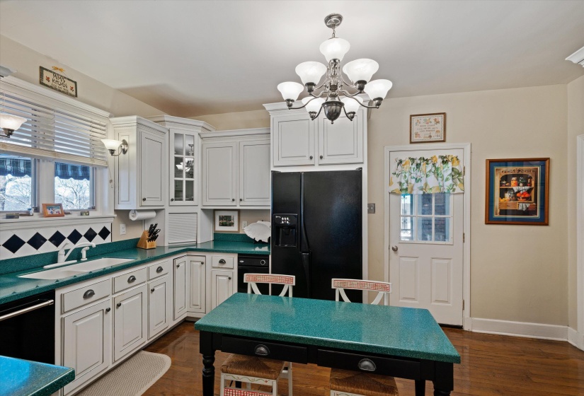 Kitchen featuring white cabinetry, a black refrigerator, a built-in dishwasher, and wood-finish flooring