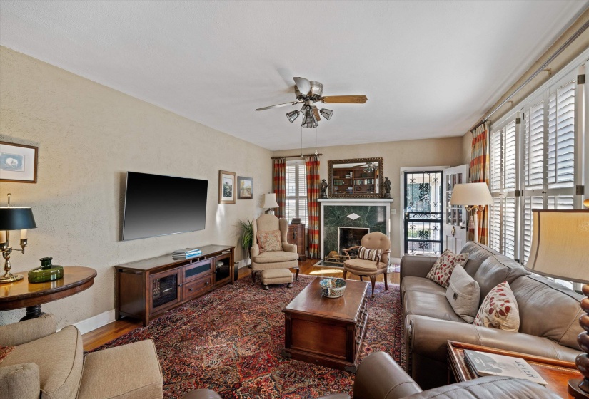 Living area featuring wood-finish flooring, a decorative fireplace with a green stone surround and white mantel, and ceiling fan