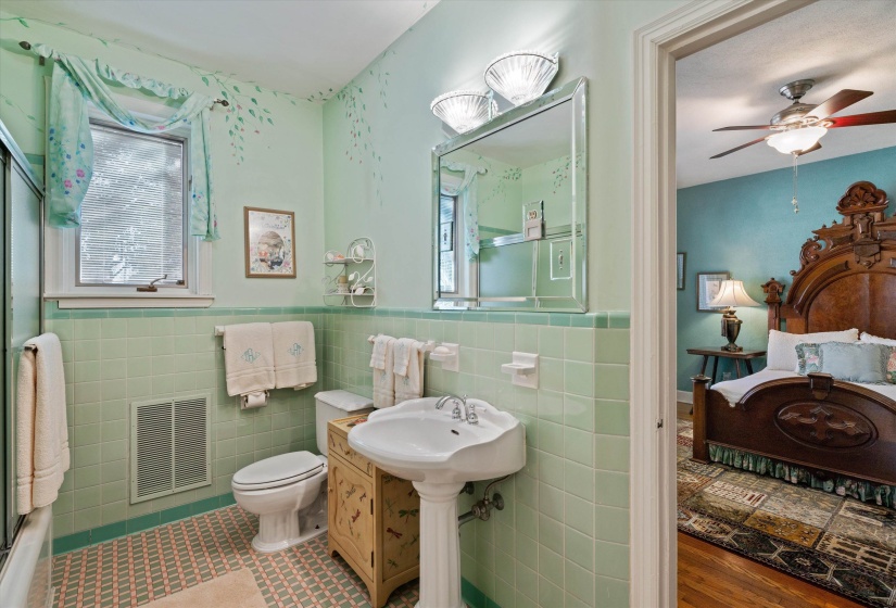 Bathroom with mint green square wall tiles, a pedestal sink, and patterned floor tiles