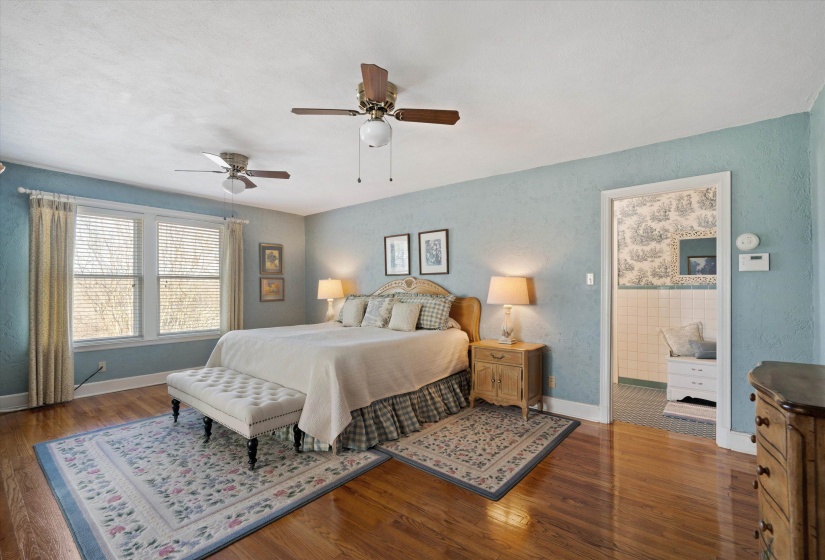 Expansive room featuring wood-finish flooring, light blue textured walls, and multiple windows with blinds