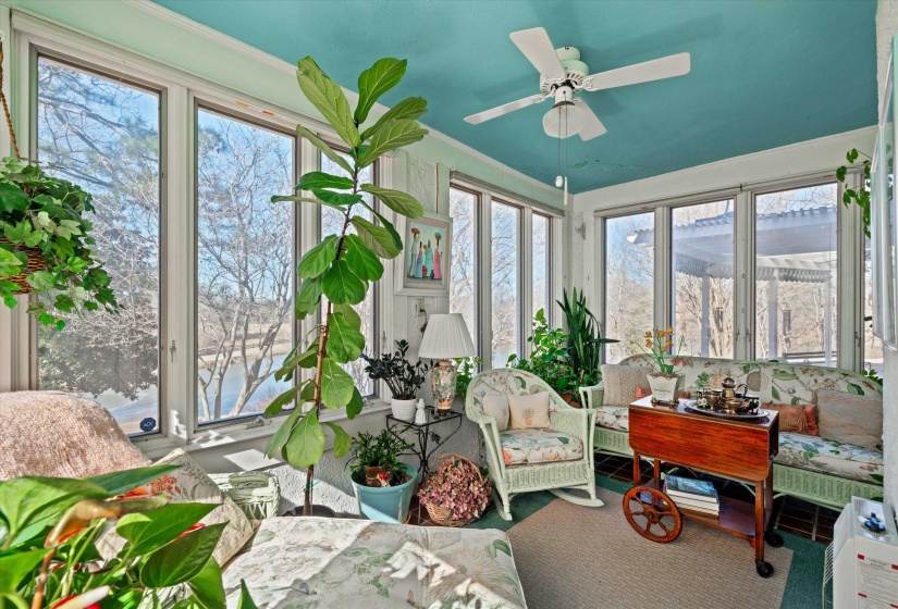 Light-filled sunroom featuring extensive window-lines, a ceiling fan, and a painted ceiling