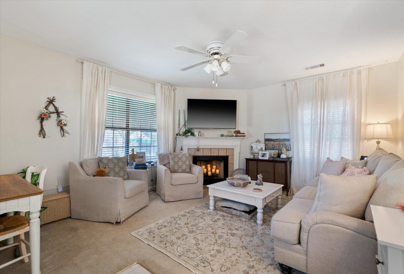 Living area featuring a corner fireplace with tile surround, white mantel, and built-in wall-mounted television