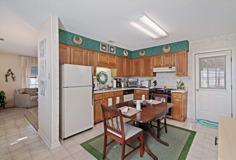 Kitchen featuring wood cabinetry, white appliances, and a built-in electric range with an overhead microwave