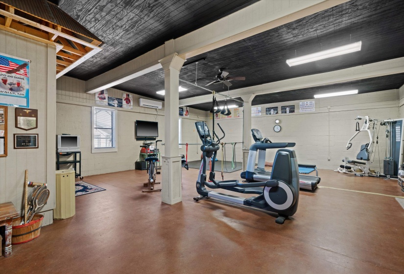 Spacious interior room with an exposed beam ceiling, painted black planks, and light-colored paneled walls