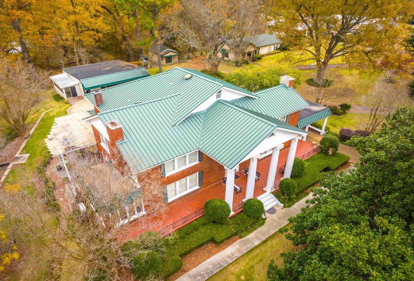 Brick exterior featuring a green standing seam metal roof, white columns, and a covered front porch