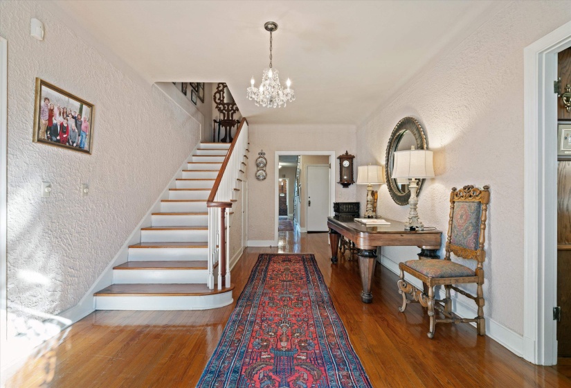 Grand entry foyer featuring hardwood flooring, a crystal chandelier, and a curved staircase with wood banister