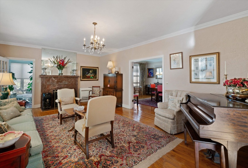 Living area featuring wood-finish flooring, an ornate chandelier, and a fireplace with a decorative mantel and hearth