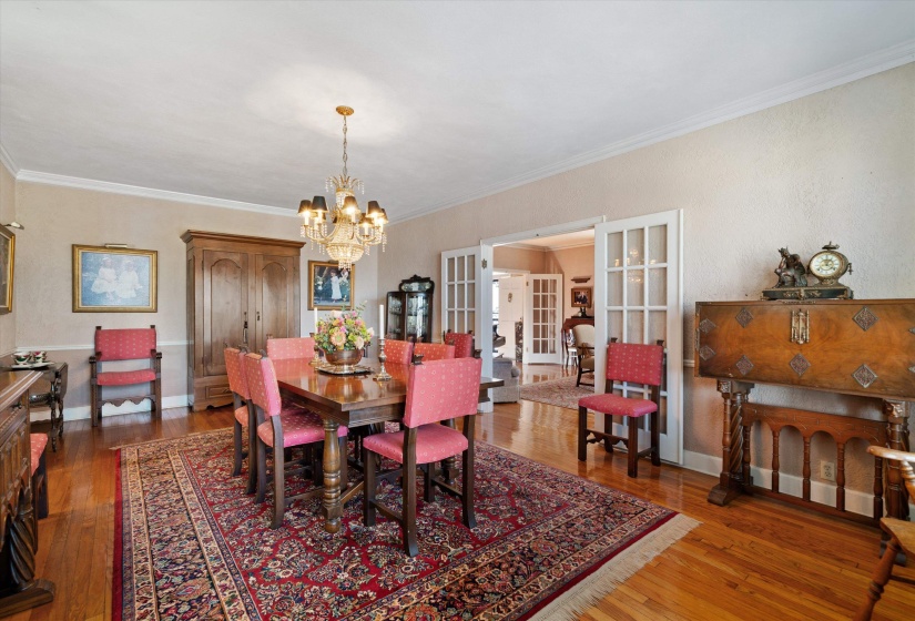 Hardwood flooring, crown molding, and a chandelier with a carved spindle base