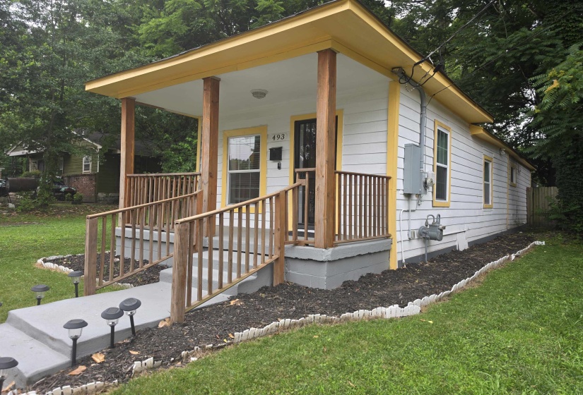 Front exterior featuring a covered porch, wood plank siding, and a concrete pathway