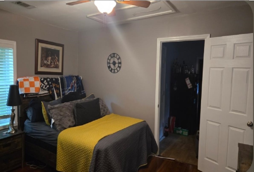Room featuring wood-finish flooring, a ceiling fan with integrated lighting, and a window with blinds