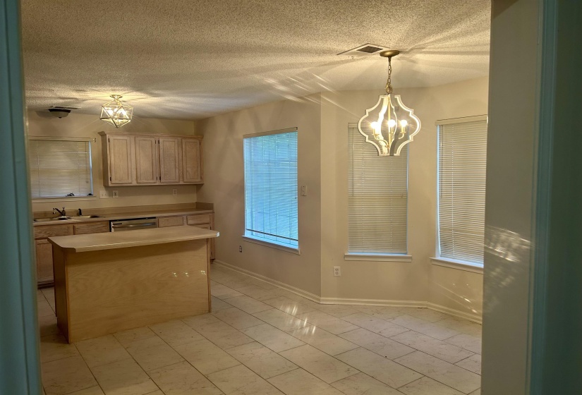 Open-concept kitchen and dining area featuring light wood-finish cabinetry, a central island, and a dishwasher