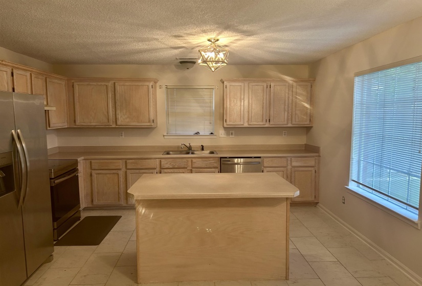Kitchen featuring wood-finish cabinetry, a central island, stainless steel appliances, and tile flooring