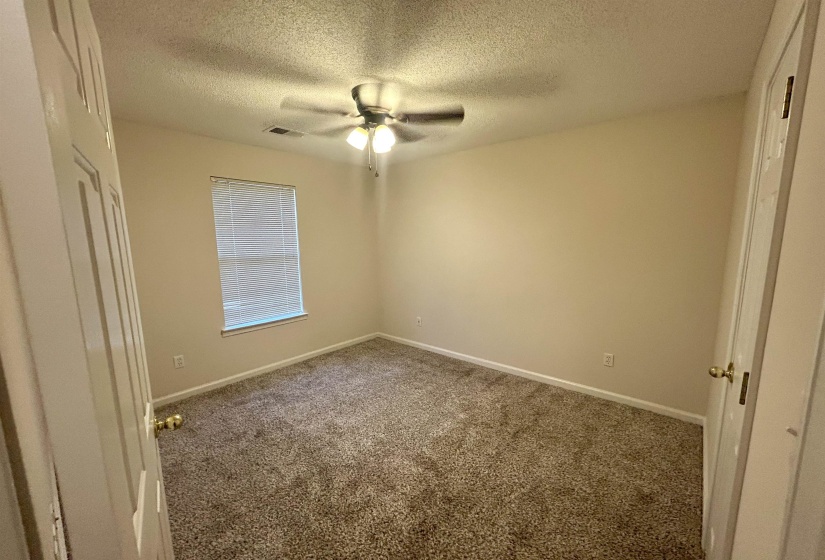 Carpeted room with neutral walls, a window featuring horizontal blinds, and a ceiling fan with integrated lighting