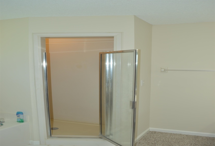 Bathroom with a stall shower, baseboards, and a garden tub