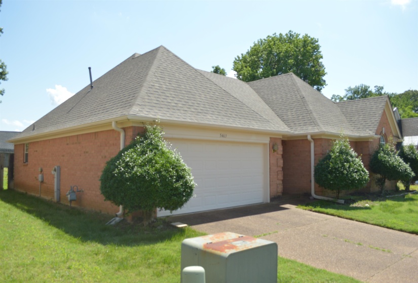 View of front of home with roof with shingles, an attached garage, a front yard, driveway, and brick siding