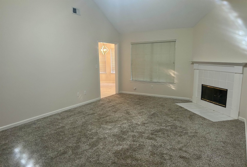 Living area featuring a vaulted ceiling and textured carpeting