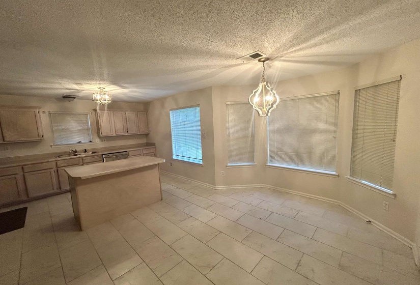 Open-concept kitchen and dining area featuring a central island, light-toned cabinetry, and tile flooring
