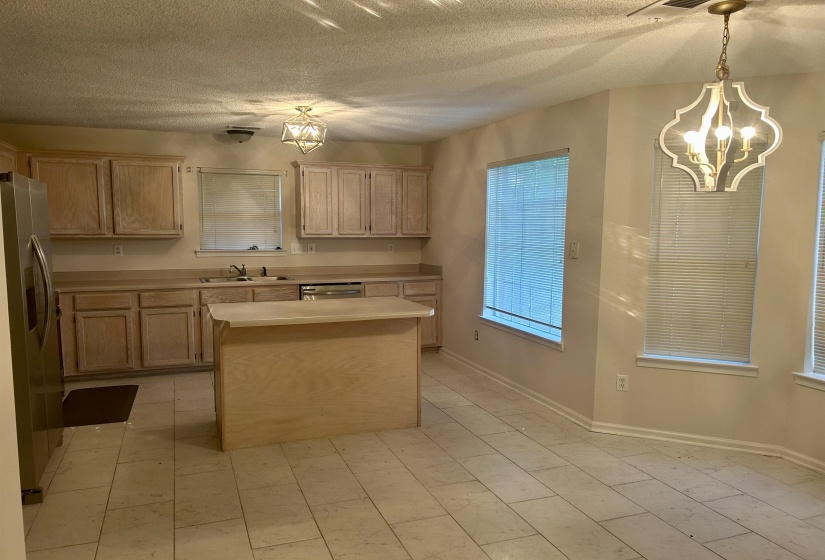Kitchen featuring light wood-finish cabinetry, a central island, and a stainless steel refrigerator