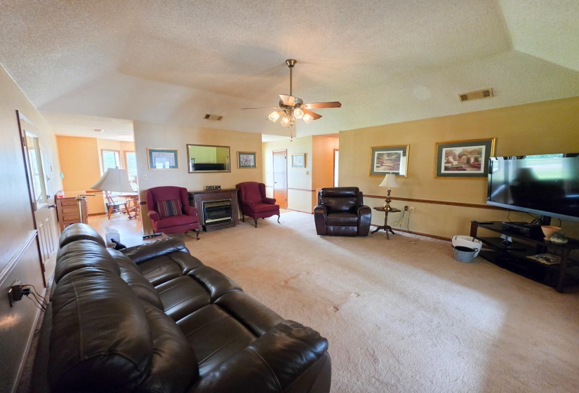 Spacious interior featuring vaulted ceilings, a ceiling fan, and carpeted flooring