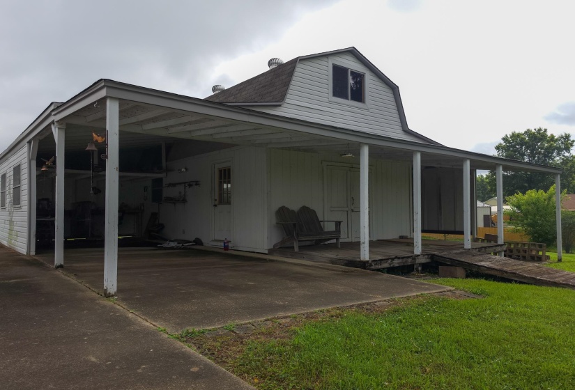 Gambrel roof structure with white siding and an extended covered patio