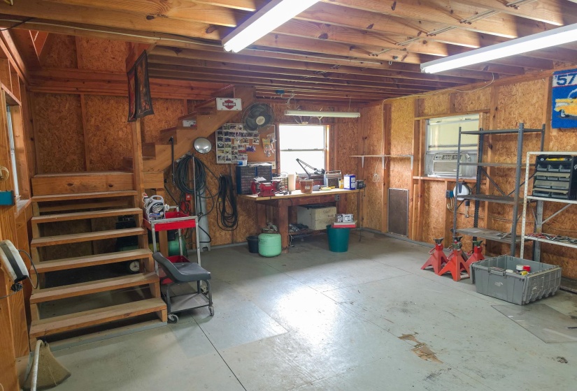 Utility space featuring an unfinished wood-paneled interior, concrete flooring, and exposed ceiling joists
