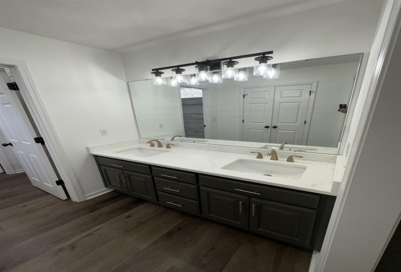 Contemporary bathroom featuring a dual vanity with dark cabinetry, white countertops, and integrated sinks