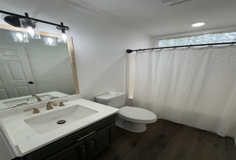 Modern bathroom featuring a dark wood-finish vanity with a white countertop and undermount sink