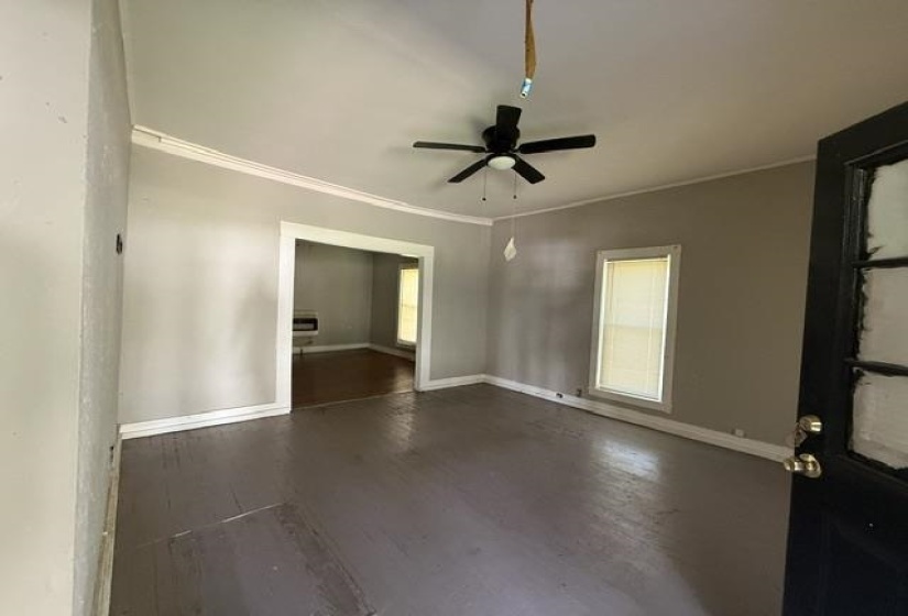 Spacious room featuring painted wood-finish flooring, a ceiling fan, and crown molding