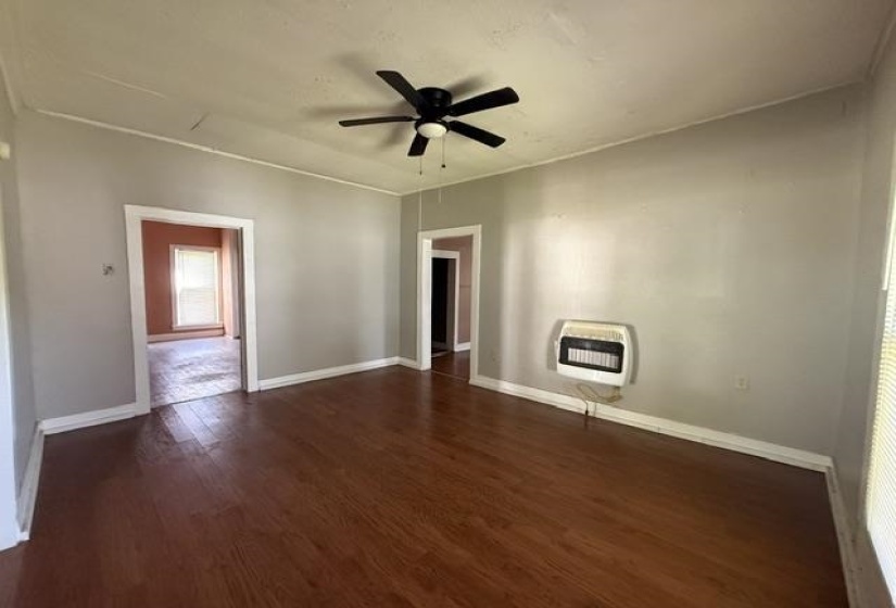 Spacious room featuring wood-finish flooring, a ceiling fan, and light gray wall tones