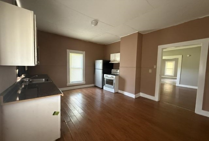 Kitchen featuring wood-finish flooring, white cabinetry, dark countertops, and essential appliances including a refrigerator and range