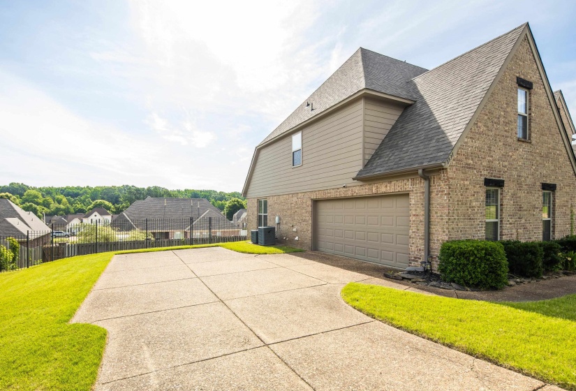Brick and siding exterior featuring a multi-car driveway, attached garage, and mature landscaping