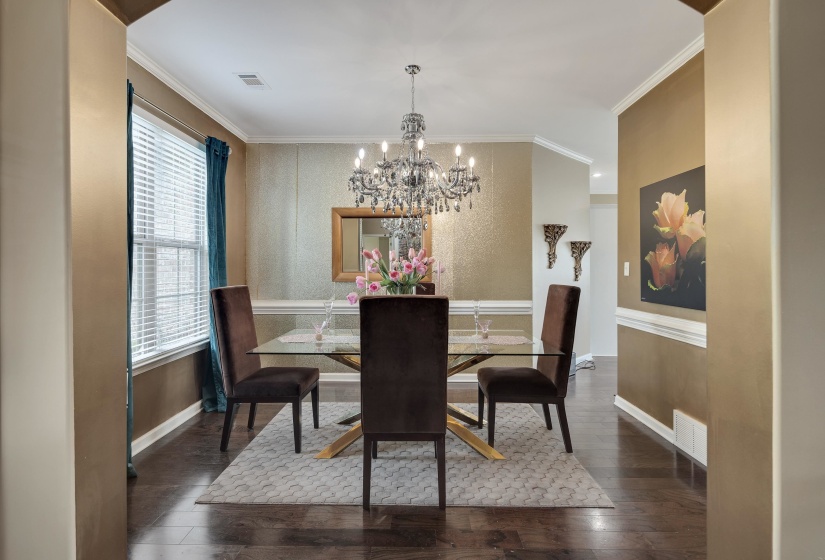 Dining area featuring wood-finish flooring, a large window, crown molding, chair rail molding, and a chandelier