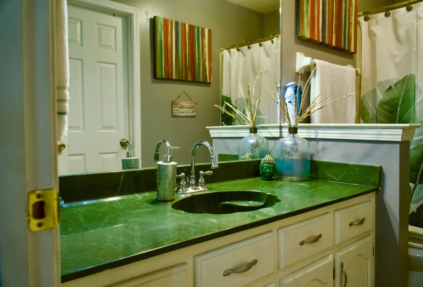 Bathroom vanity featuring a green countertop with an integrated sink and chrome faucet