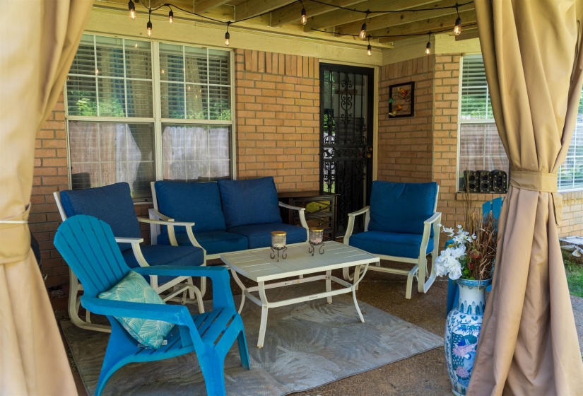 Covered patio featuring string lighting, a brick exterior wall, and a full-light entry door with security screen