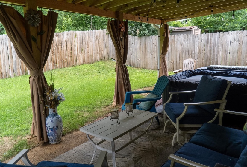 Covered patio featuring string lighting, privacy drapes, and a concrete surface