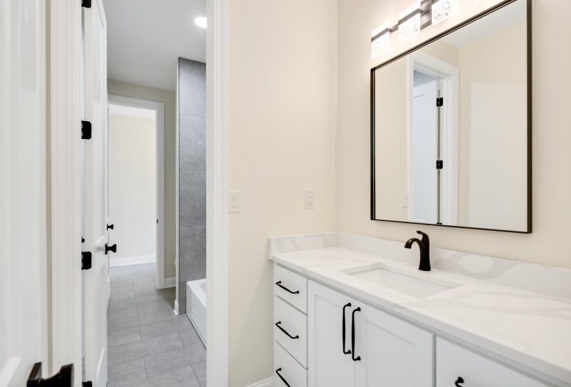 Bathroom vanity featuring a white countertop with integrated sink, matte black faucet, and rectangular mirror with a black frame