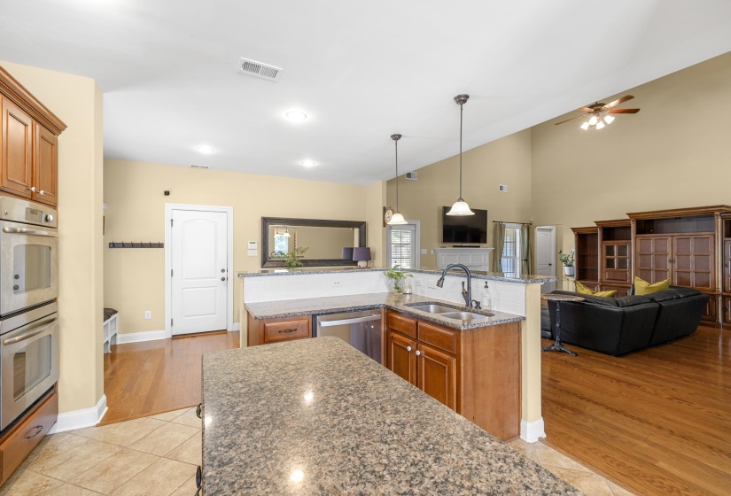 Kitchen featuring granite countertops, wood-finish cabinetry, stainless steel double ovens, and a stainless steel dishwasher