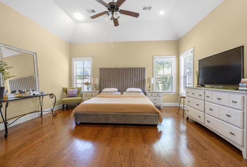 Spacious room featuring vaulted ceilings, wood-finish flooring, and two windows