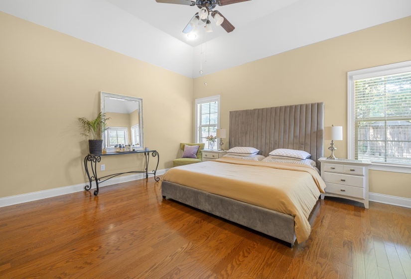 Vaulted ceiling with an attached fan, hardwood flooring, and light-toned walls