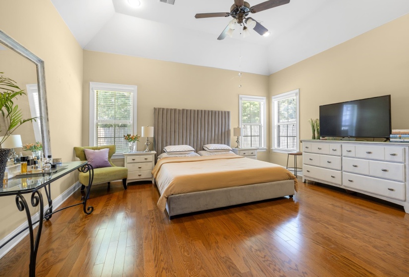 Varnished wood-finish flooring complements the room's high vaulted ceiling and ceiling fan
