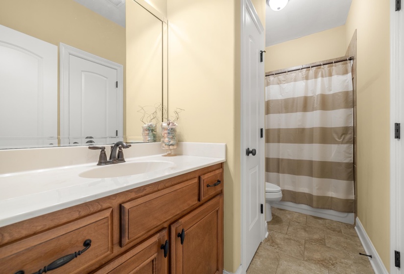 Bathroom featuring a vanity with a white countertop, oval sink, bronze-finish faucet, and wood-finish cabinetry with dark hardware