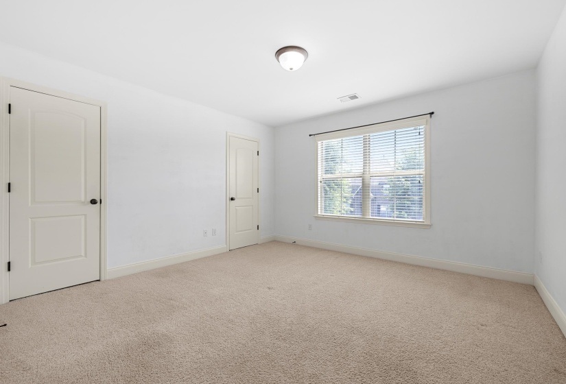 Carpeted room featuring white walls, a single window with blinds, and two panel doors with black hardware