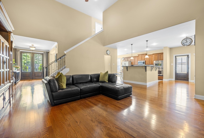 Vaulted ceiling living area featuring wood-finish flooring, a wrought iron staircase railing, and recessed lighting